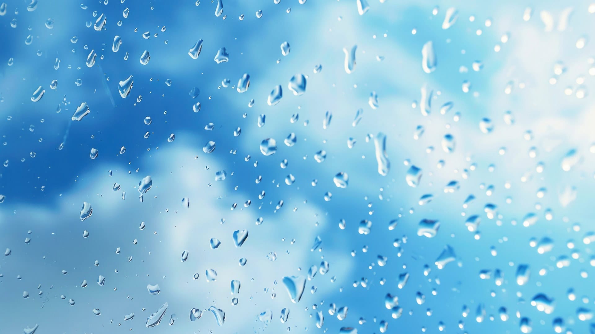 Regentropfen am Fenster mit blauem Himmel im Hintergrund. Perfekt für Wetter- oder Naturkonzepte