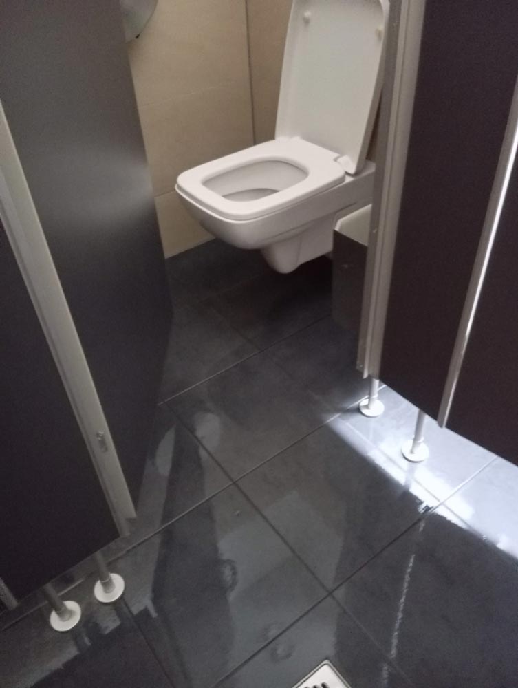 Eine saubere, leere Toilette mit schwarzem Fliesenboden.