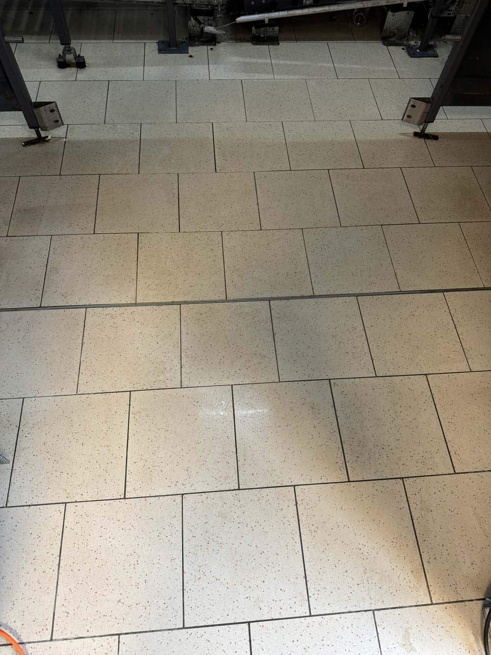 Bild von weißem Fliesenboden, helles Licht reflektiert, dunkle Ränder zwischen den Fliesen.